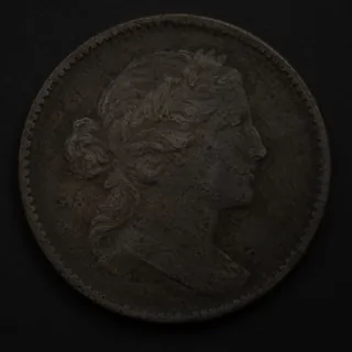 An underlit coin with its surface detail in shadow.